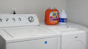 A white Bosch washing machine with a control panel and two detergent bottles on top.