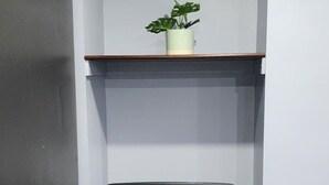 A corner office with a black office chair, a potted plant on a shelf, and wooden shelving units.