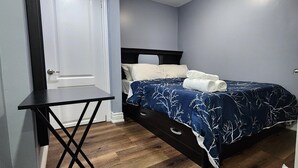 A bedroom with a bed, a nightstand, and a door.