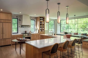 A spacious kitchen with a large island, wooden cabinets, and pendant lighting.