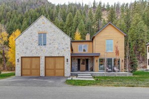 A two-story house with a stone facade and a wooden extension, garage doors, and a driveway.