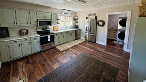 Eine Küche mit hellgrünen Schränken, einem Edelstahl-Kühlschrank, einer Mikrowelle und einem eingebauten Backofen.