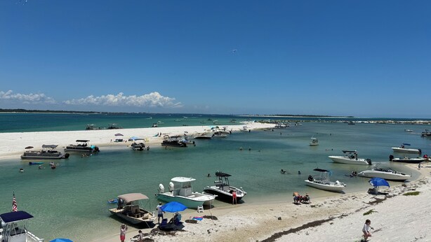 A beach with boats, umbrellas, and people. - Charming 4-bedroom barndominum in Elberta with AC, WiFi, 5 miles from boat ramp
 (Elberta)