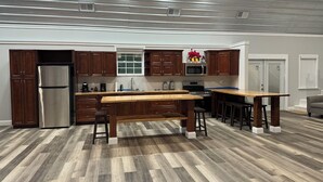A modern kitchen with wooden cabinets, stainless steel appliances, and a central island with stools. - Charming 4-bedroom barndominum in Elberta with AC, WiFi, 5 miles from boat ramp
 (Elberta)