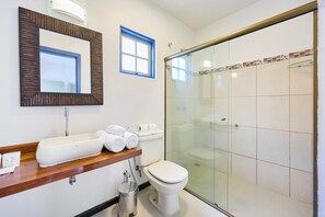 A bathroom with a glass shower enclosure, a white toilet, and a sink with a mirror above it. - Casa Poema Paraty (Paraty)
