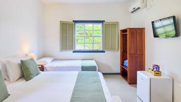 Ein Hotelzimmer mit zwei Betten, einem Fernseher, einem kleinen Kühlschrank und einem Fenster mit Rollläden.