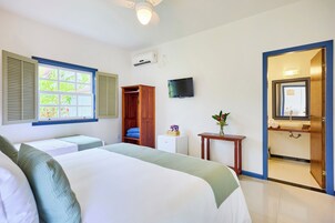 Een hotelkamer met een bed, een televisie, een kledingkast, een klein tafeltje, en een badkamer die door een open deur zichtbaar is.