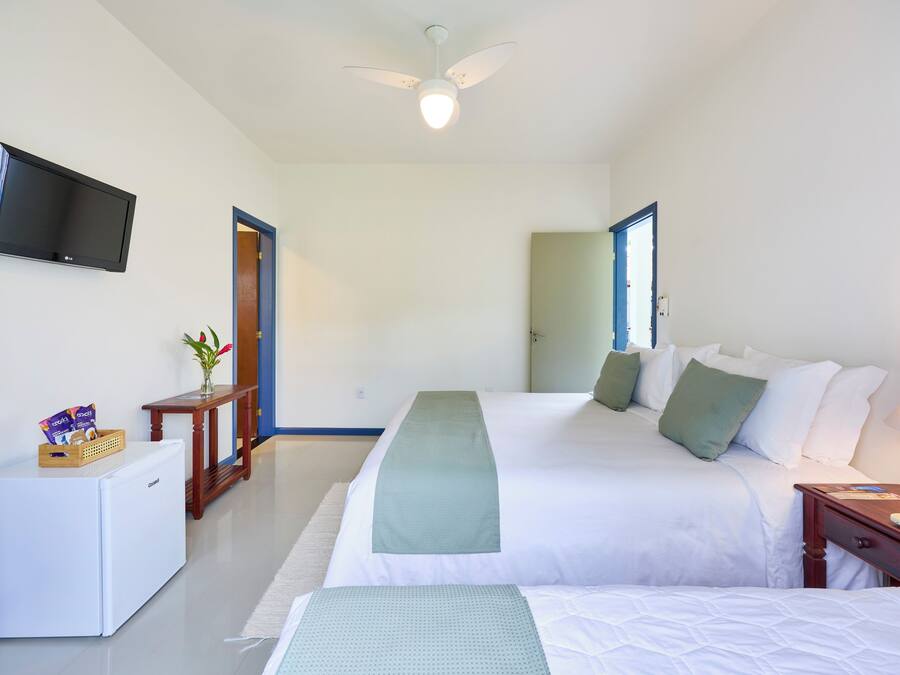 A hotel room with a bed, a desk, a television, and a small refrigerator.