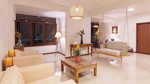 A spacious living room with a sofa, a coffee table, a hanging chair, and a wooden table with a vase of flowers. - Casa Poema Paraty (Paraty)