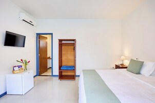 Een hotelkamer met een bed, een kledingkast, een bureau met een flatscreen televisie en een airconditioning.