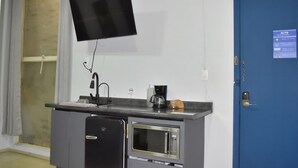 A kitchenette with a microwave, coffee maker, and a flat-screen TV mounted on the wall.