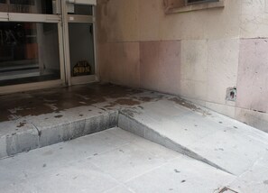 Exposed stone facade with a tiled floor and a small opening in the wall.