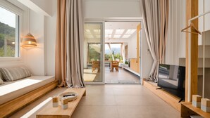 A modern living room with a large TV, wooden furniture, and a view of the outdoors. - Escape to Aristi Dio – where nature meets luxury in Halkidiki (Olympiada)