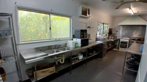 A kitchen with stainless steel appliances, a large window, and a ceiling fan. - Stay on Mer (Murray Island)