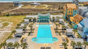 Un resort con piscina central, varias habitaciones de huéspedes y vista al mar.