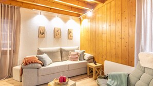 A cozy living room with a sofa, cushions, a small wooden table with candles, and wooden wall decor.