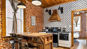 Una cocina con una isla de madera, taburetes de bar, estufa y microondas.