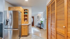 A modern kitchen with a stainless steel refrigerator, wooden cabinets, and a built-in shelf unit.
