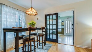 A dining area with a table and chairs, a hanging light fixture, and a potted plant.