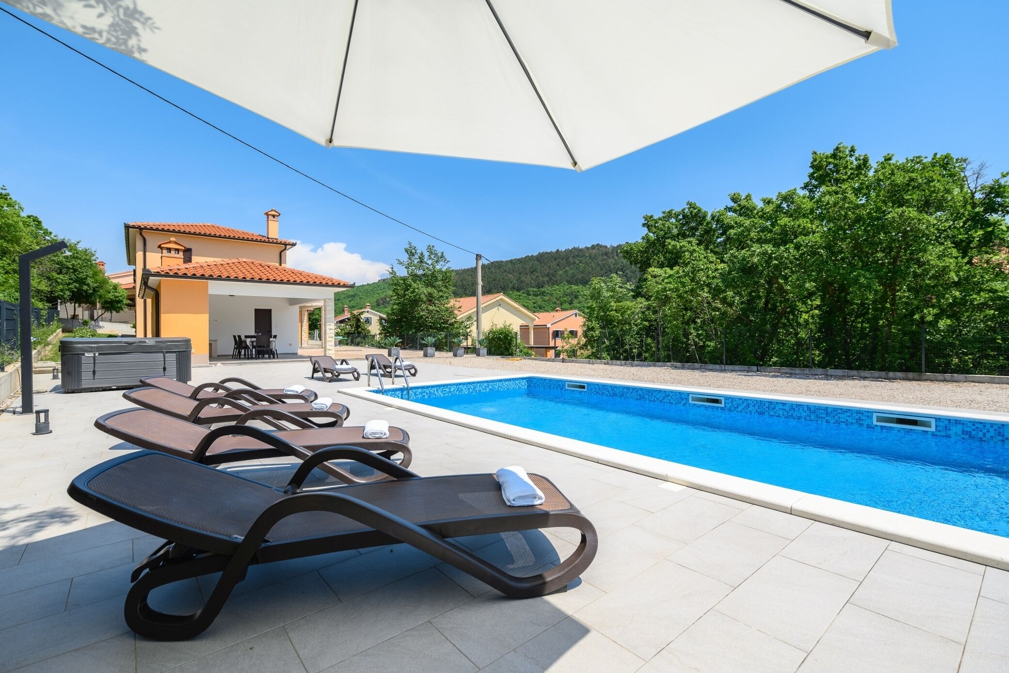 A swimming pool area with lounge chairs and a covered seating area.