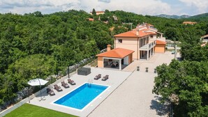 Une villa dotée d’une piscine, d’un espace extérieur aménagé et offrant une vue sur la forêt environnante.
