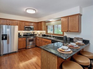 A modern kitchen with wooden cabinets, stainless steel appliances, and a granite countertop.