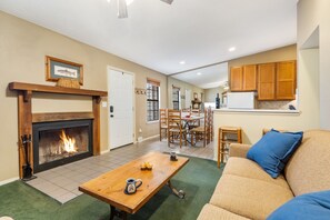 A living room with a fireplace, a dining area, and a kitchen with wooden cabinets.