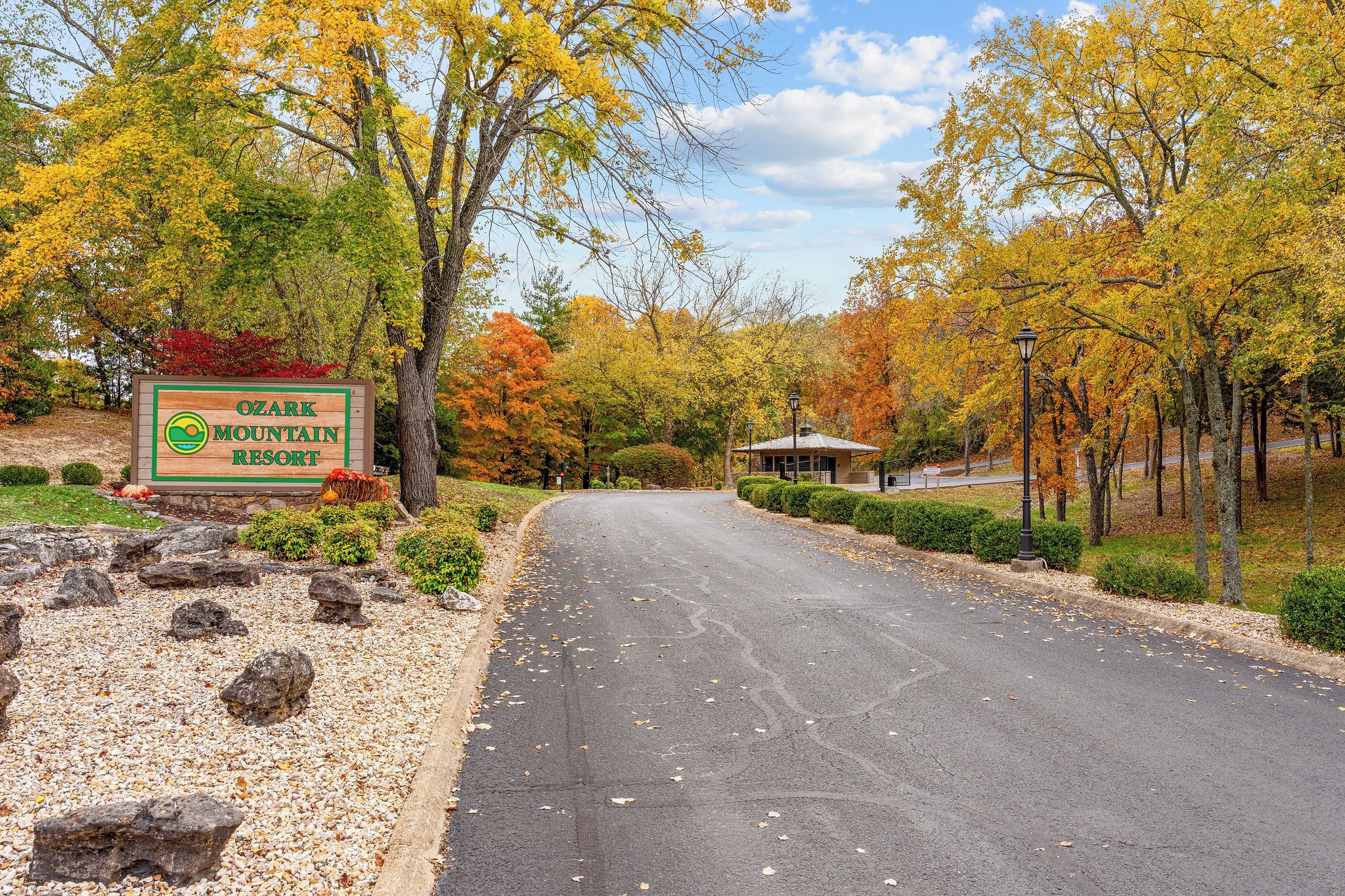 A road leading to Ozark Mountain Resort with a signboard, surrounded by autumn foliage.