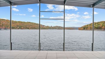 A covered outdoor area with a view of a lake and hills in the background.