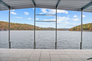 A covered outdoor area with a view of a lake and hills in the background.