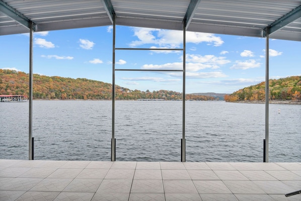 Un espacio al aire libre techado con vista a un lago y colinas al fondo.