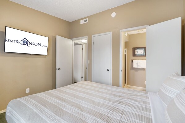 Een hotelkamer met een bed, een aan de muur bevestigde televisie en een deur naar een badkamer.