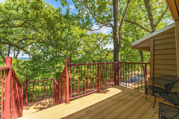Um deck de madeira com guarda-corpo vermelho, com vista para uma área arborizada.