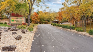 A sign for Ozark Mountain Resort with a paved road leading to a building.