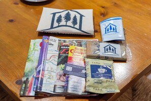 Una mesa de madera con diversos objetos, como un mapa, un paquete de café, un folleto turístico y un paquete de café con la marca.