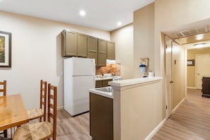 Une cuisine de taille réduite, équipée d’un réfrigérateur, d’une cuisinière et de meubles de rangement en bois.