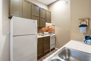 Una cocina compacta con refrigerador, estufa y pileta.