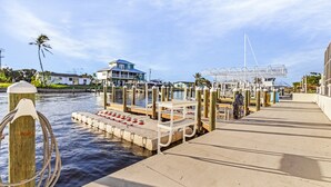 A waterfront dock with a wooden walkway, a white bench, and a metal structure. - 1/1 Condo in St. James City! Boat Slip Included! (Saint James City)