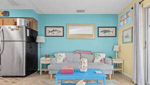 A kitchen with a refrigerator, a blue table, and a sofa with decorative pillows. - 1/1 Condo in St. James City! Boat Slip Included! (Saint James City)