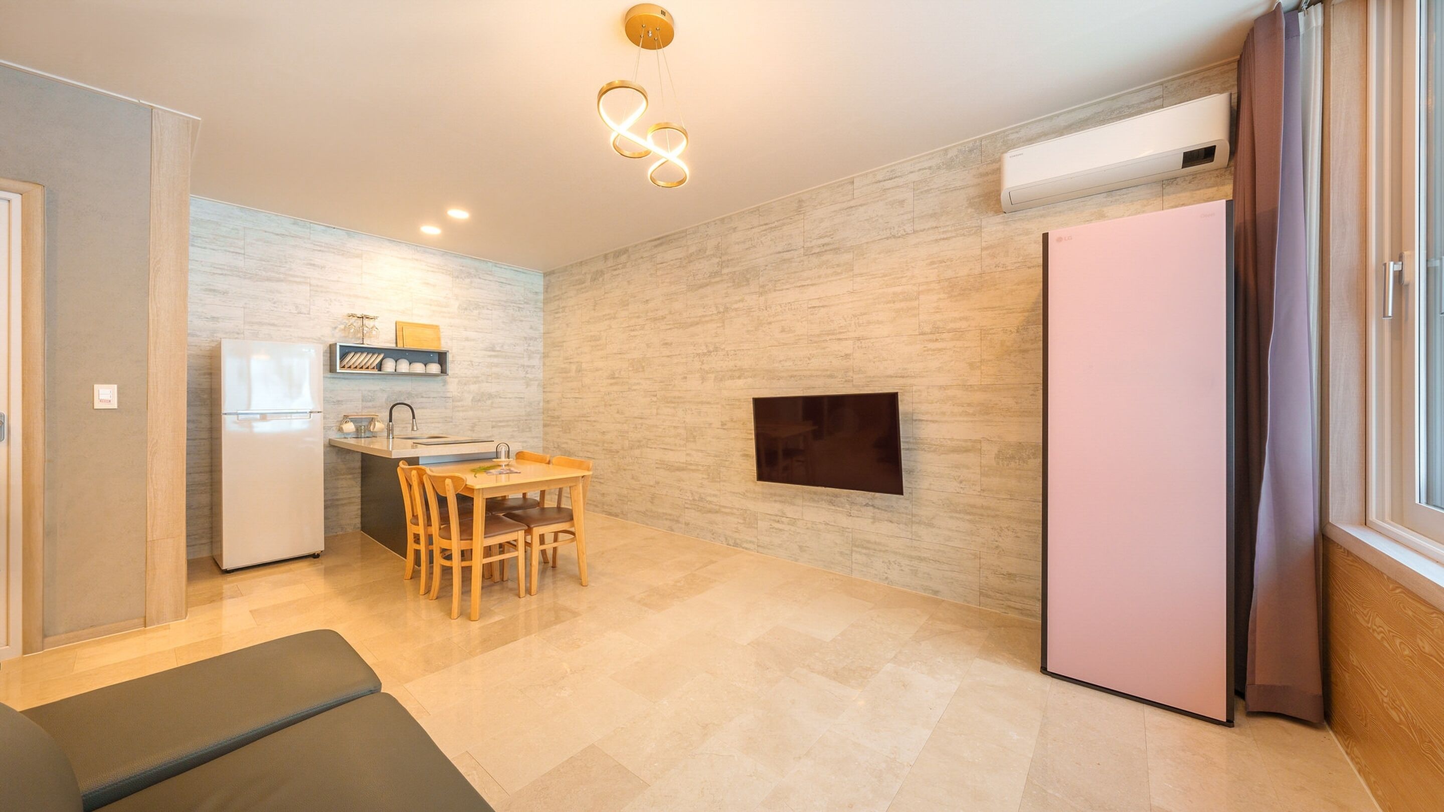 A compact kitchen with a dining area, a built-in TV, and a large window with curtains.