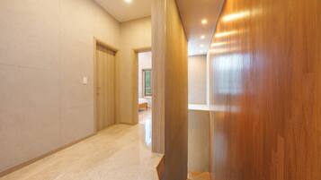 A hallway with a wooden door, a bed, and a window.