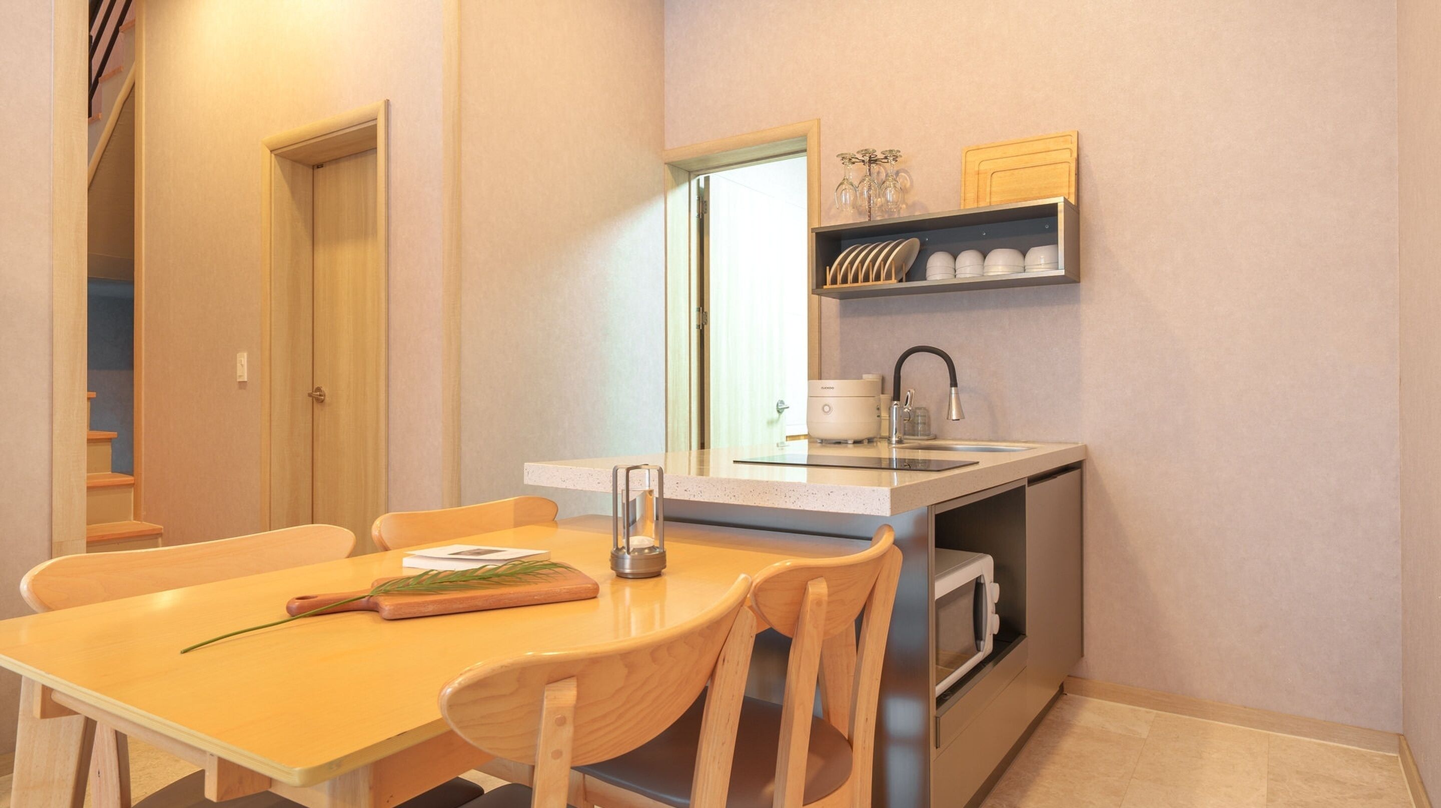 A compact kitchen with a dining table, chairs, a coffee maker, and a microwave.