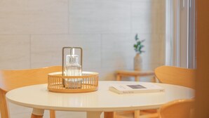 Een ronde tafel met een glazen fles, een houten standaard, een boek getiteld 'Bartim Springs' en een vaas met groene planten op de achtergrond.