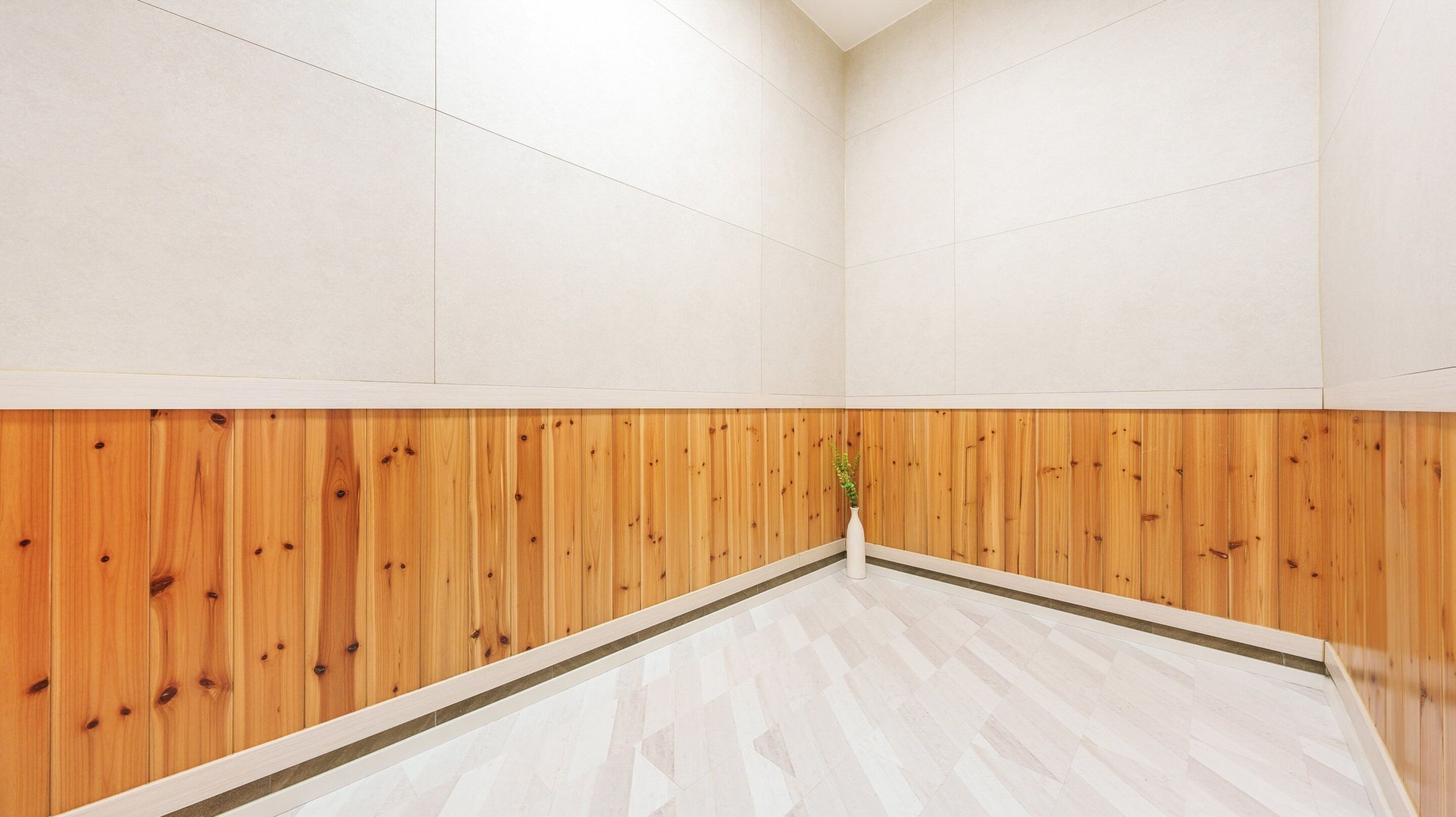 Habitación con la mitad inferior de madera y la mitad superior de color blanco, y un piso con estampado de espiga.