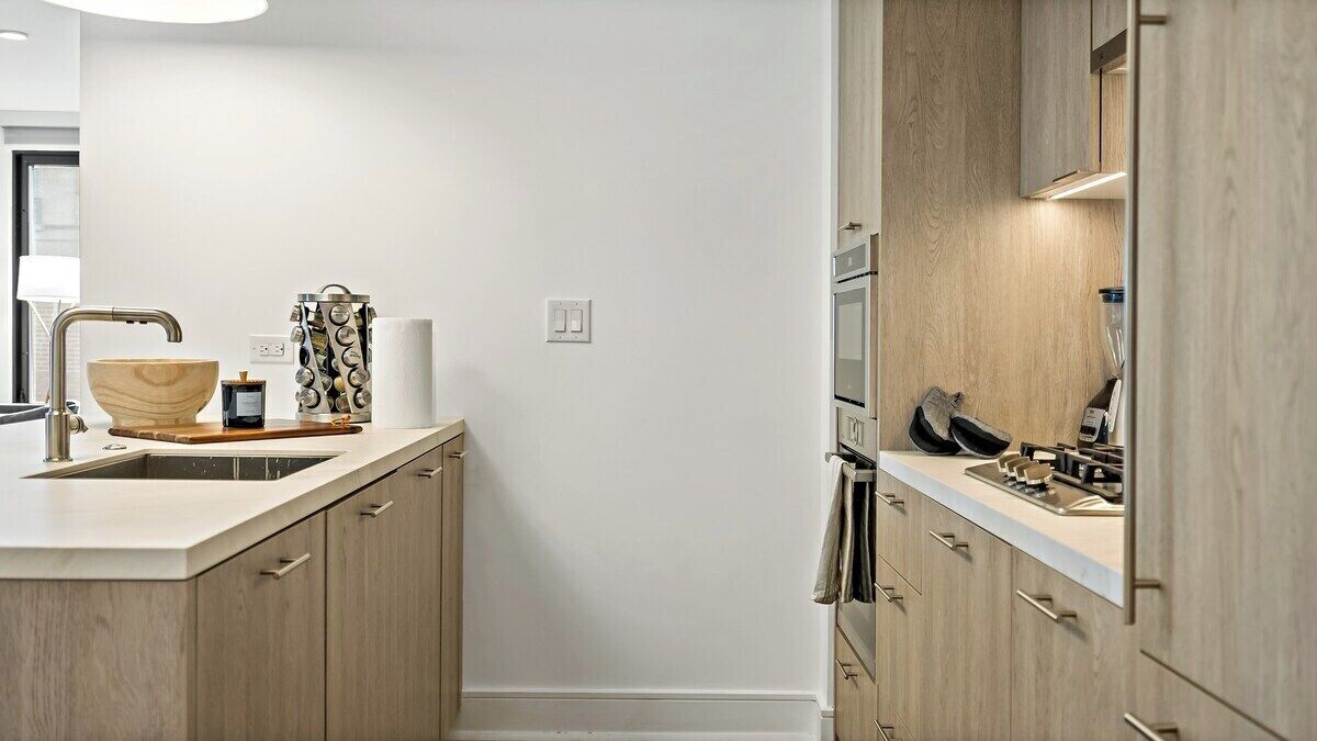 A modern kitchen with wooden cabinets, a large island with a sink, and built-in appliances.
