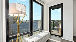 Una habitación moderna con ventanas amplias, un sofá blanco y una lámpara de pie.