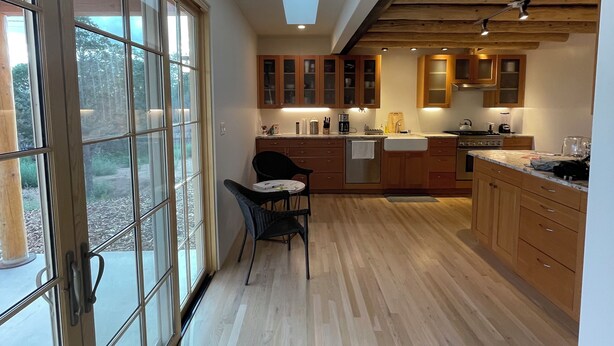A modern kitchen with wooden cabinets, a skylight, and a dining area with a table and chairs. - Lovely Home on Museum Hill-walk to Plaza/Canyon Rd (Santa Fe)