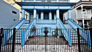 A two-story building with a blue exterior, a front porch, and a staircase leading to the entrance. - Grand Victorian in Mansion Flats - 3BR/1.5BA (Sacramento)