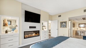 A bedroom with a fireplace, a TV mounted on the wall, and a desk with a chair.