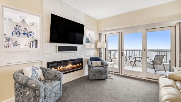 A modern living room with a fireplace, a television, and a balcony with outdoor furniture.